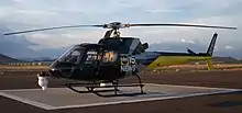 A black, gray, and yellow helicopter on a landing pad