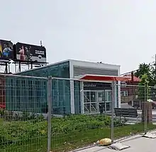 Photo of small, glass panelled subway station entrance with greenery beside it.