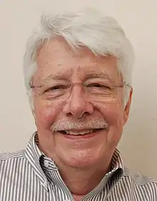 A white-haired man with moustache and glasses