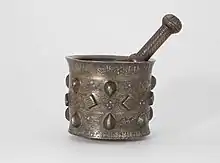 Pestle and mortar made of brass or quaternary copper alloy, piece cast, engraved, ringmatted and inlaid with silver, copper and a black compound.