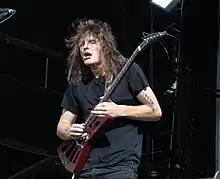 Stu Mackenzie playing guitar and headbanging during a concert.