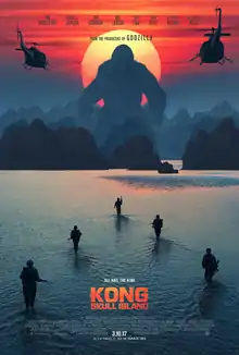 Kong standing right front of the sun, near the hills and soldiers chasing him in the water.