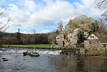 A mill on the left, surrounded by cliffs.