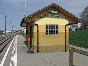 Covered waiting area with gabled roof on side platform