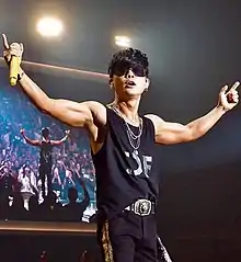 Lee Seung-hwan holding a microphone in one hand with both arms in the air