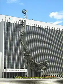 Picture of the monument, a crescent-like stone artwork covered with several bronze statues.