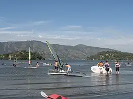 Windsurfers on a lake, with hills beyond