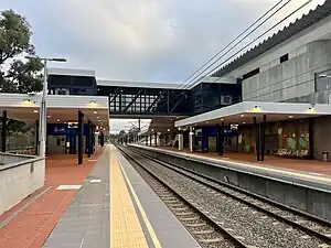 View from platform of two paved side platforms with large shelters and an overpass linking the two