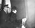 LST-344 launching, 15 December 1942. Mrs. Bonnie Ward, Wife of H.H. Ward, Master Machinist, Inside Machine Shop Master, christens the ship at Norfolk Navy Yard, Portsmouth, Virginia with Lieutenant R. I. Coleman, Aide to the Commandant, also on the platform.