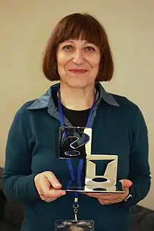 Middle-aged brunette woman holding an award.