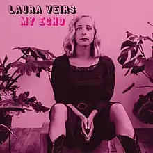 A pink and magenta monochromatic photo of Veirs seated