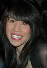 Long-haired Asian-American woman smiling to a camera