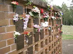 Columbarium wall, with flowers, plaques, and empty niches