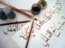 The instruments and work of a student calligrapher. The phrase written on the top of the paper shows the Shiite saying "Every day is Ashura and every land is Karbala."