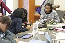 three people are using books and talking around a small table