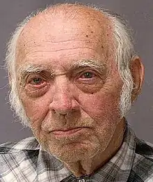 Close-up headshot of an old balding white male with white hair