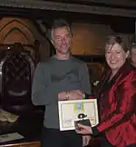 Minister Lianne Dalziel shaking Robert Ibell's hand and holding a certificate and a trophy