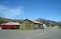 View from the northern side of the surprisingly large former yard at Little River. The main road from Christchurch to Akaroa runs behind the station, which is visible above the guard's van.