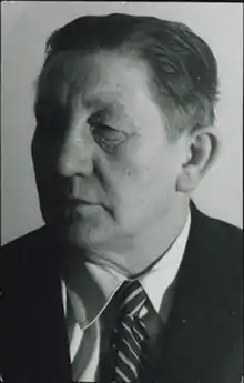 A black and white portrait of a masculine woman in a suit and tie.