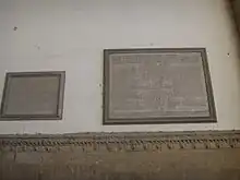 Two plaques on a white wall from a low point of view.