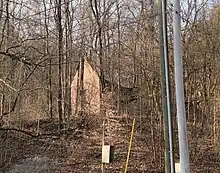 Long Schoolhouse pictured through the trees. The roof has caved in and it is in a state of disrepair.