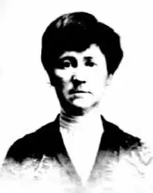 A middle-aged white woman wearing a light blouse and a dark jacket