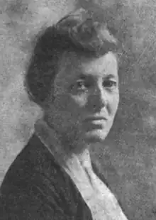 A middle-aged white woman, hair in a simple updo, wearing a shirt and jacket