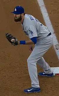 A man in a red baseball jersey with "Sounds" written on the front in white and blue and a blue cap with a white "N" on the center stands on a baseball field swinging a bat.