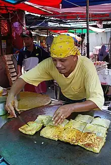 Image 41Murtabak being made at a stall, a type of pancake filled with eggs, small chunks of meat and onions. (from Malaysian cuisine)