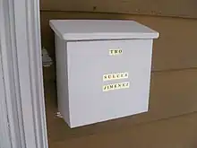 A white mailbox, attached to a wall