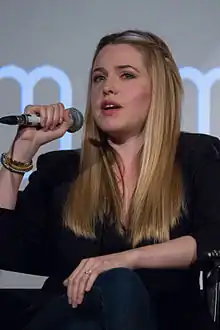 Delfino holding a microphone while seated