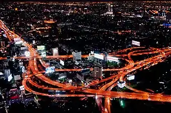 Night photograph looking down at a large elevated road interchange; many billboards along the roads