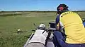 Close view of one a shooter with a monitor besides him for electronic scoring.