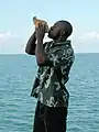 Man in olive Androsia blowing conch shell