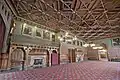 Gothic style Banqueting Room, Manchester Town Hall, showing a typical later style Waterhouse ceiling, note the fireplaces with stone fire-surrounds with tiled interiors and solid wooden over-mantles, on the left is an upper gallery with wrought-iron balustrade, for musicians to play on, the pendant light fittings are the original gasoliers converted to electricity.