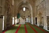 View of the mosque's prayer hall, with the mihrab on the left and the entrance portal on the right. The minbar is also visible past the mihrab.