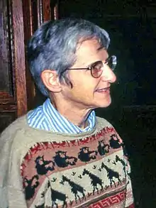 Gray-haired woman in sweater with African animal motifs standing in profile