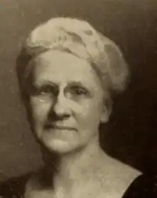 An older white woman with white hair, wearing eyeglasses