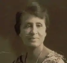 Photograph of a black woman in a sleeveless sheath wearing pearls.