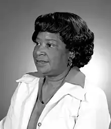 Mary Jackson poses for a portrait; she wears a collared, bright-white, business-professional jacket overtop another large-collared shirt. Jackson’s short, bob-style hair (with curls in the back) subtly frames her face while she smiles calmly, looking off to the side.