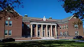 large brick building with six tall columns having Ionic capitals at the center entrance