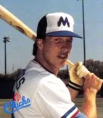 A man in a white baseball uniform holding a bat on his shoulders