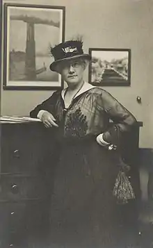  Photo shows Mattie Edwards Hewitt, three-quarter length portrait, standing, facing front, right arm on chest of drawers.