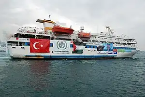 Photo of white cruiser yacht, adorned with banners of Turkey and Palestine