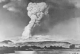 Mushroom-shaped cloud with long neck above a line of ridges