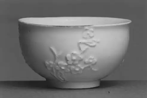 A cup made at Meissen Porcelain Manufactory, Germany, ca. 1725-1730. Although long-known in China, the technique of making true or hard-paste porcelain was not rediscovered in Europe until J. F. Böttger's experiments at Meissen in the early 18th century. This little porcelain cup with its applied prunus or plum blossom decoration reflects the influence of a Chinese, "Blanc de Chine" porcelain prototype.