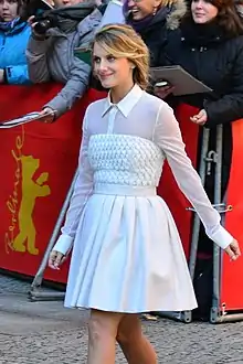 Laurent in a white dress looking away from the camera.