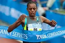 Photo of Meseret Hailu reaching the finish line ribbon