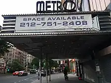 Side view of the Metro Theater, a three-story movie theater. The main entrance is to the right, and a large rectangular marquee is located above the entrance.