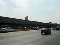 Picture of the station in the middle of Río Consolado Avenue. Several automobiles surround the station.